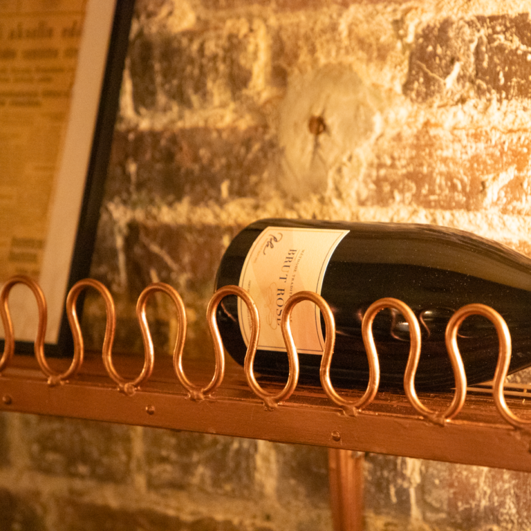 Brut Rosé -viinipullo kuparisella hyllyllä tiiliseinää vasten